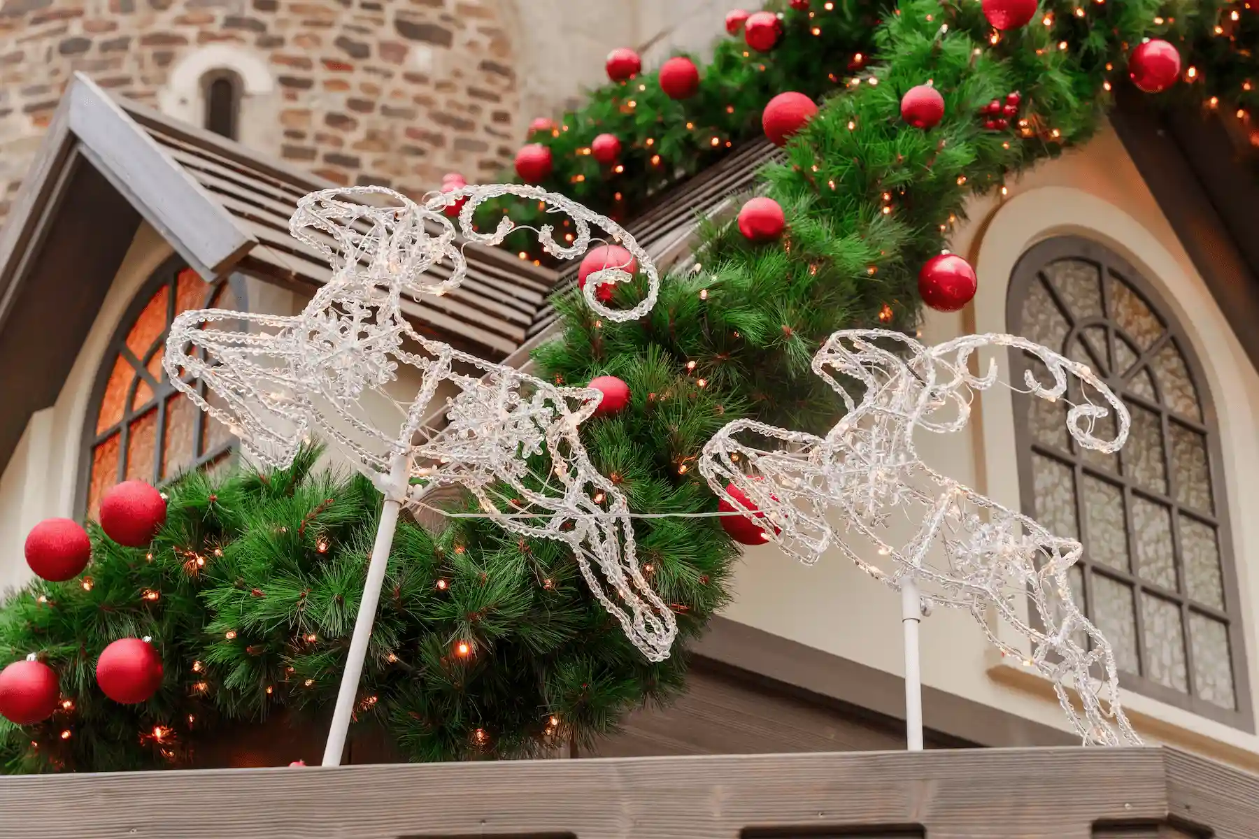 Renne luminose e ghirlande con palline rosse sopra una finestra ad arco - mercatini di Natale di Faenza