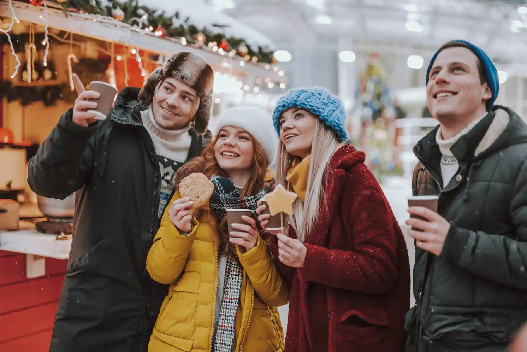 Gruppo di amici con biscotti e bevande calde davanti alle casette - mercatini di Natale di Fossombrone