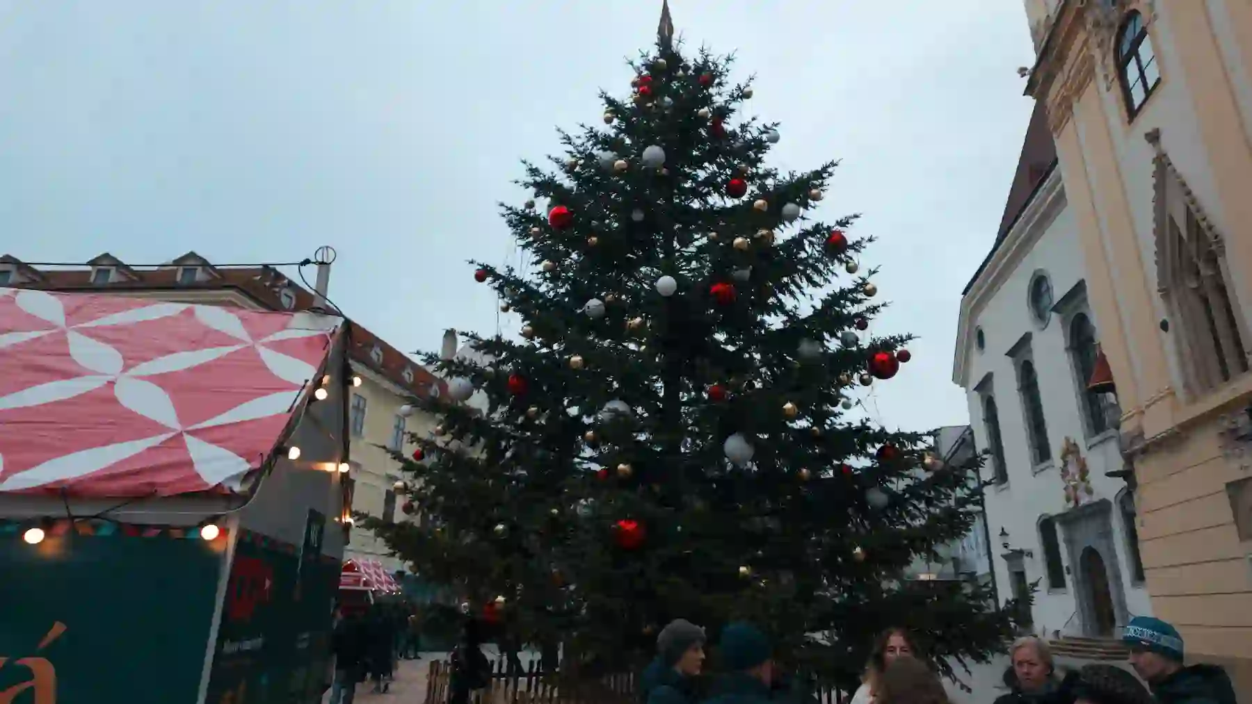 Grande albero di Natale con palline rosse in una piazza circondata da palazzi - mercatini di Natale di Ravenna