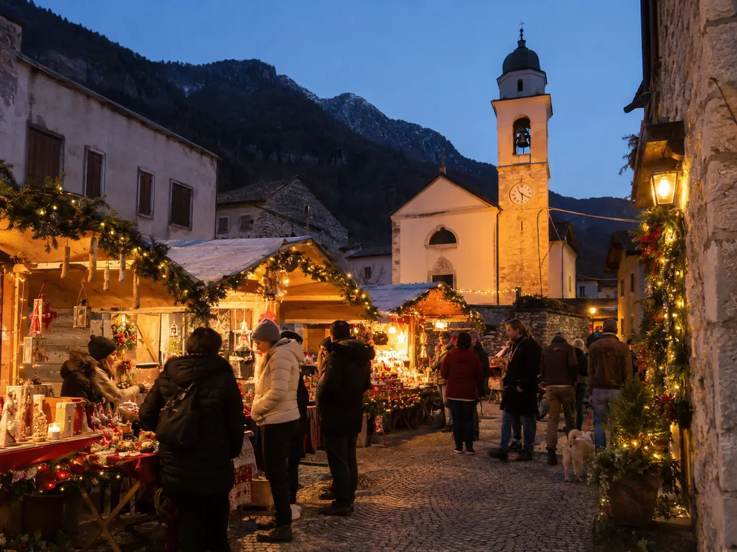 Casette di Natale tra la chiesa con campanile e le case in pietra, con le montagne sullo sfondo, mercatini di Natale di Rosà