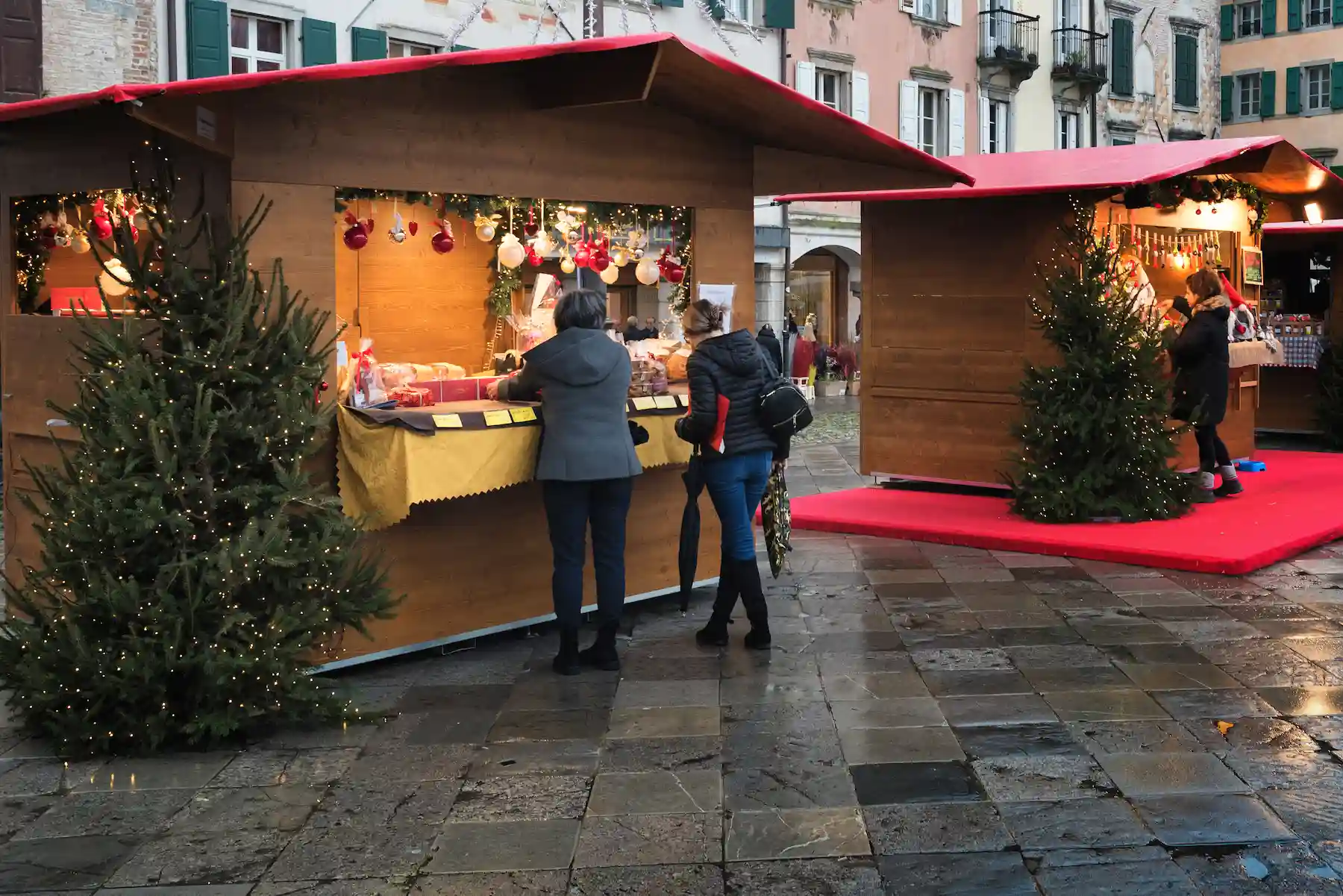 Casette di legno con abeti in una piazza lastricata del centro - mercatini di Natale di Udine